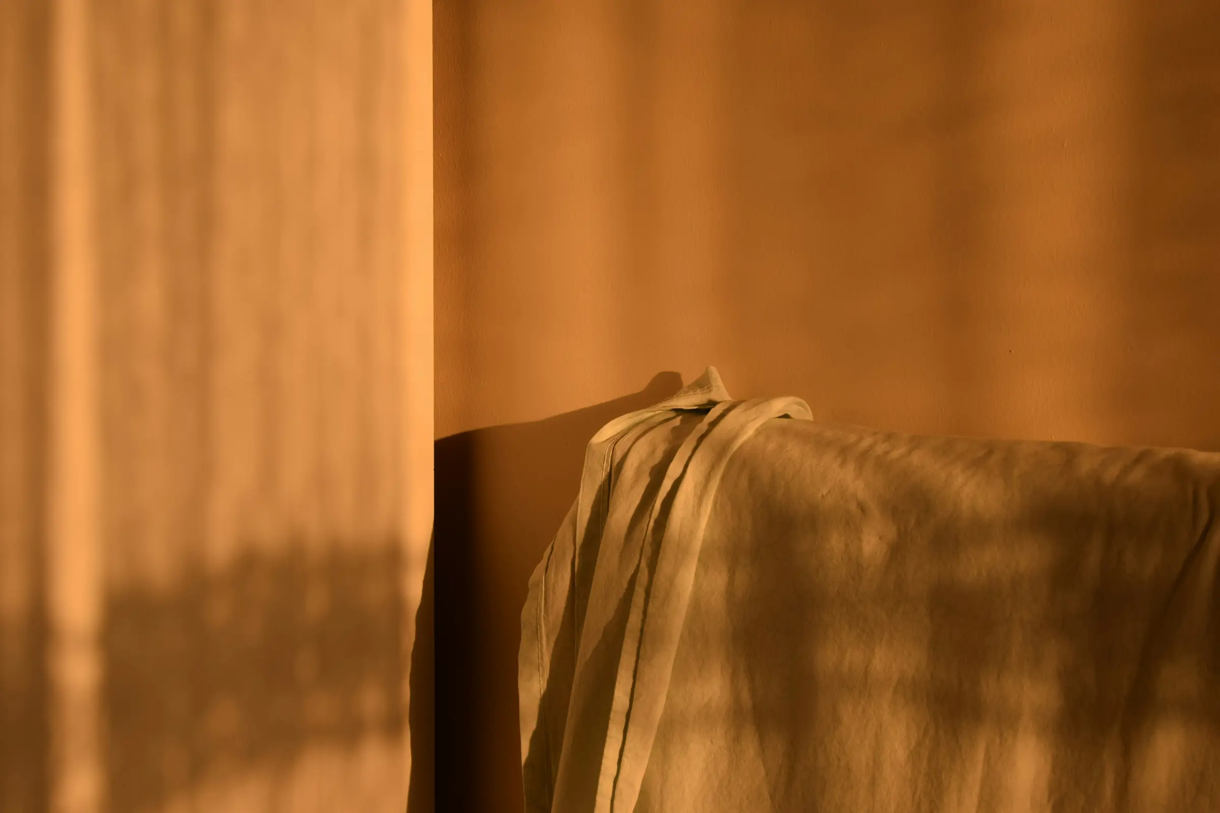 Late sun coming through a sheer curtain onto folded linen.