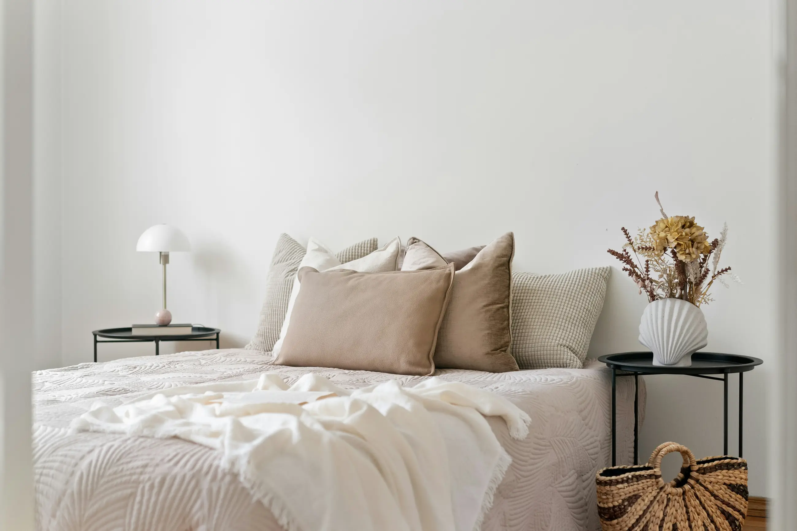A pale room with linen cushions and woven baskets by the bed.