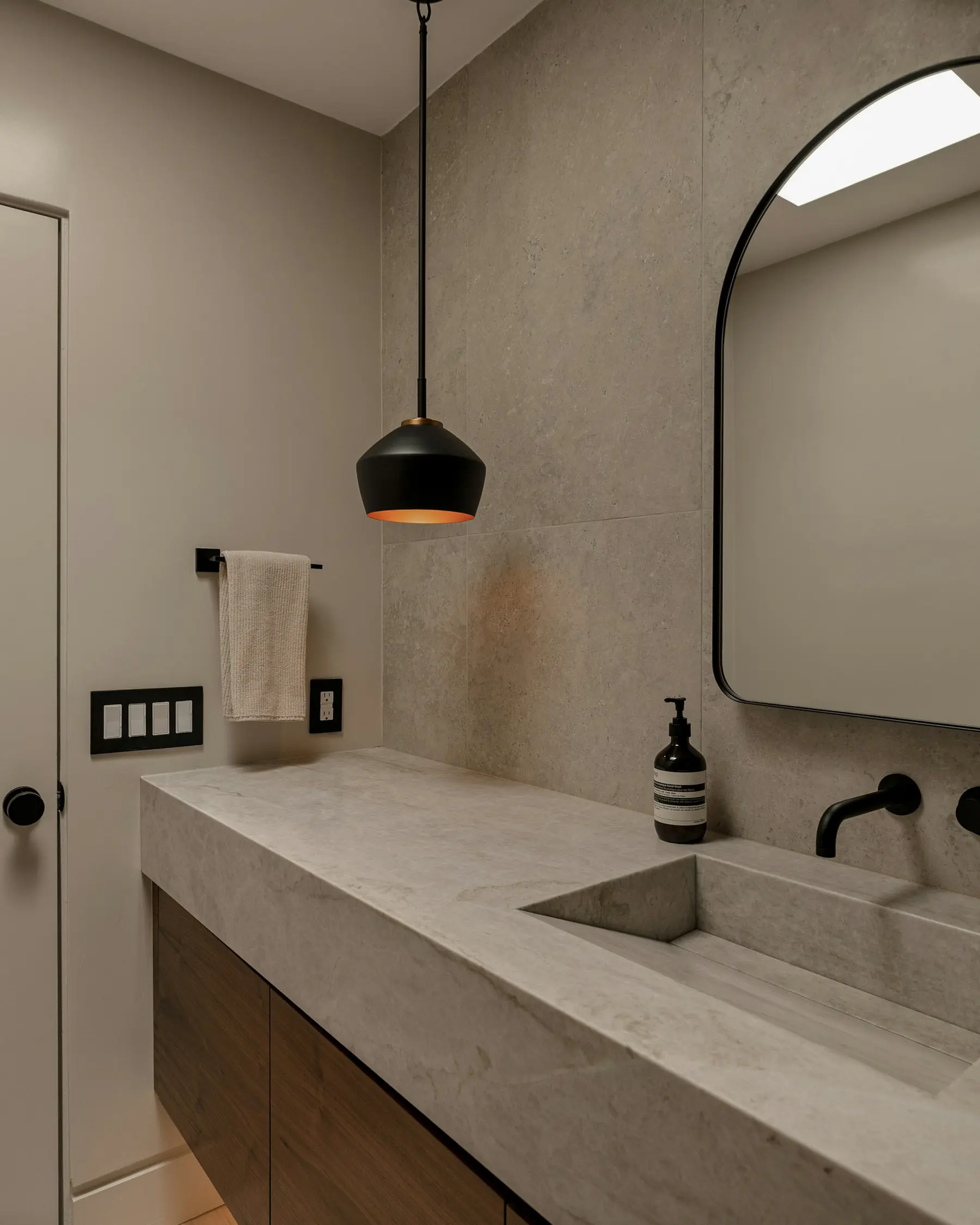 A poured stone basin and a plain mirror in the ensuite.